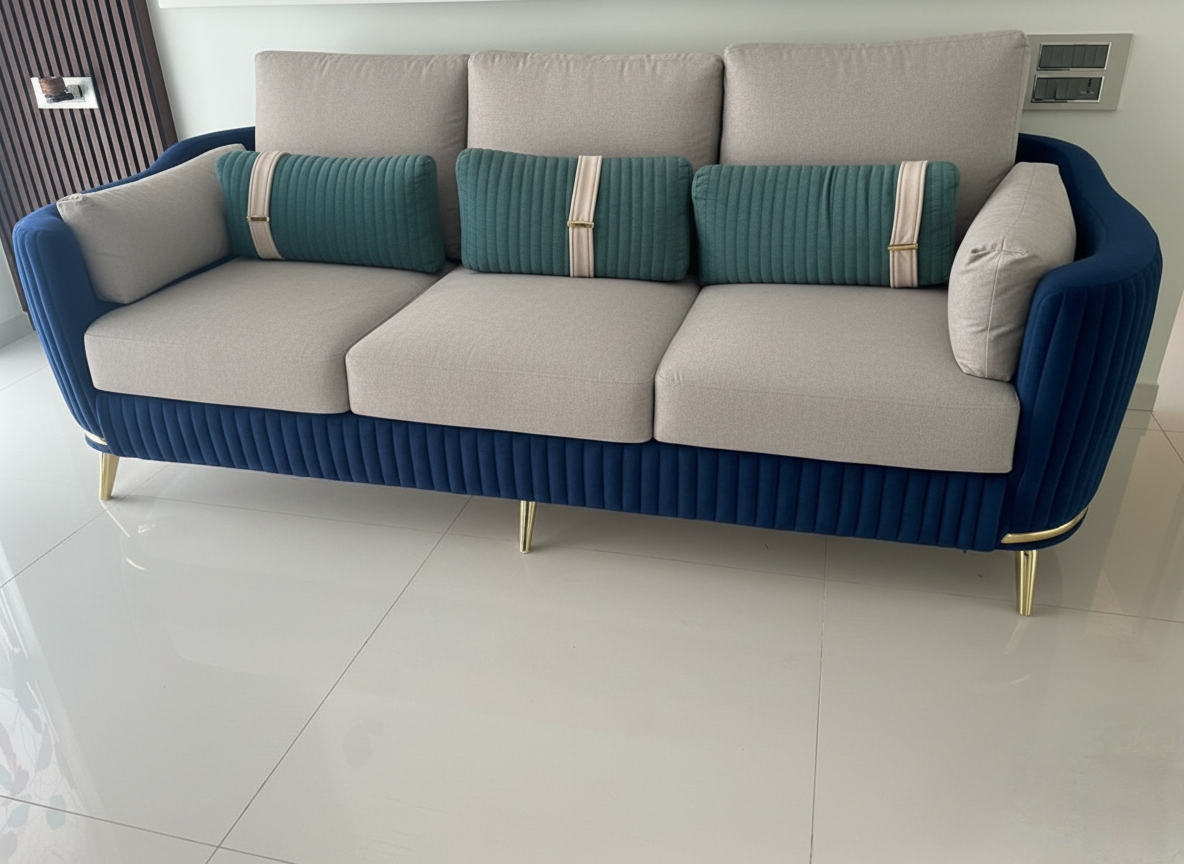 Royal blue and beige sofa with teal accent cushions and gold legs on a glossy white floor