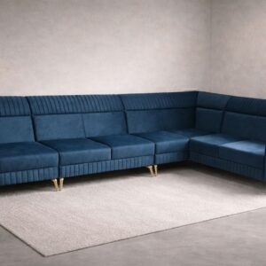 Navy blue velvet L-shaped sectional sofa with gold legs and matching ottomans styled in a minimal modern room.
