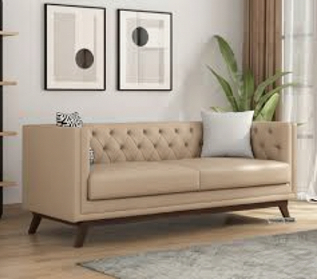 Beige tufted sofa in a modern living room with abstract framed art, light curtains and indoor plant.