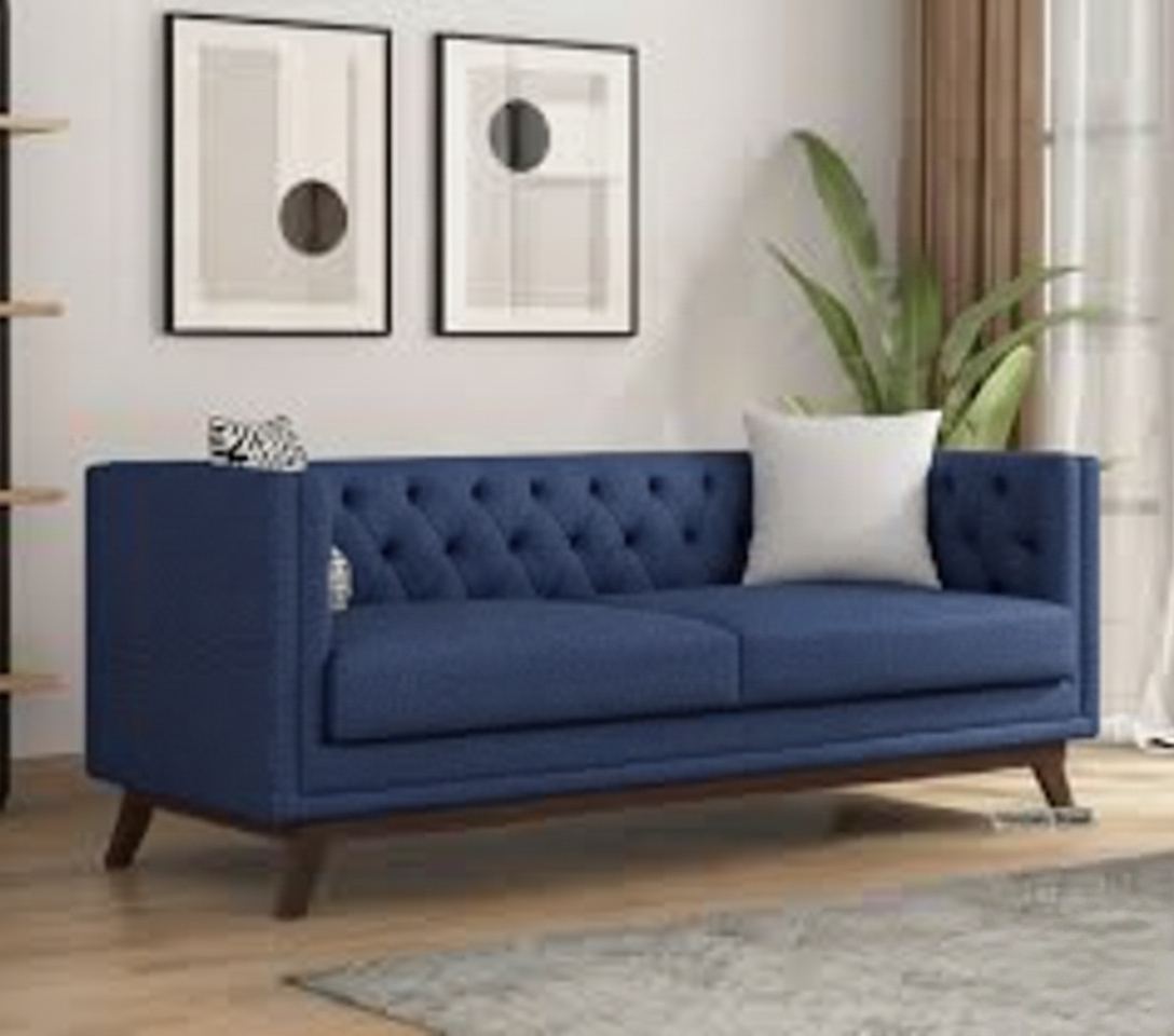 Royal blue tufted sofa in a stylish modern living room with abstract wall frames and indoor plant.