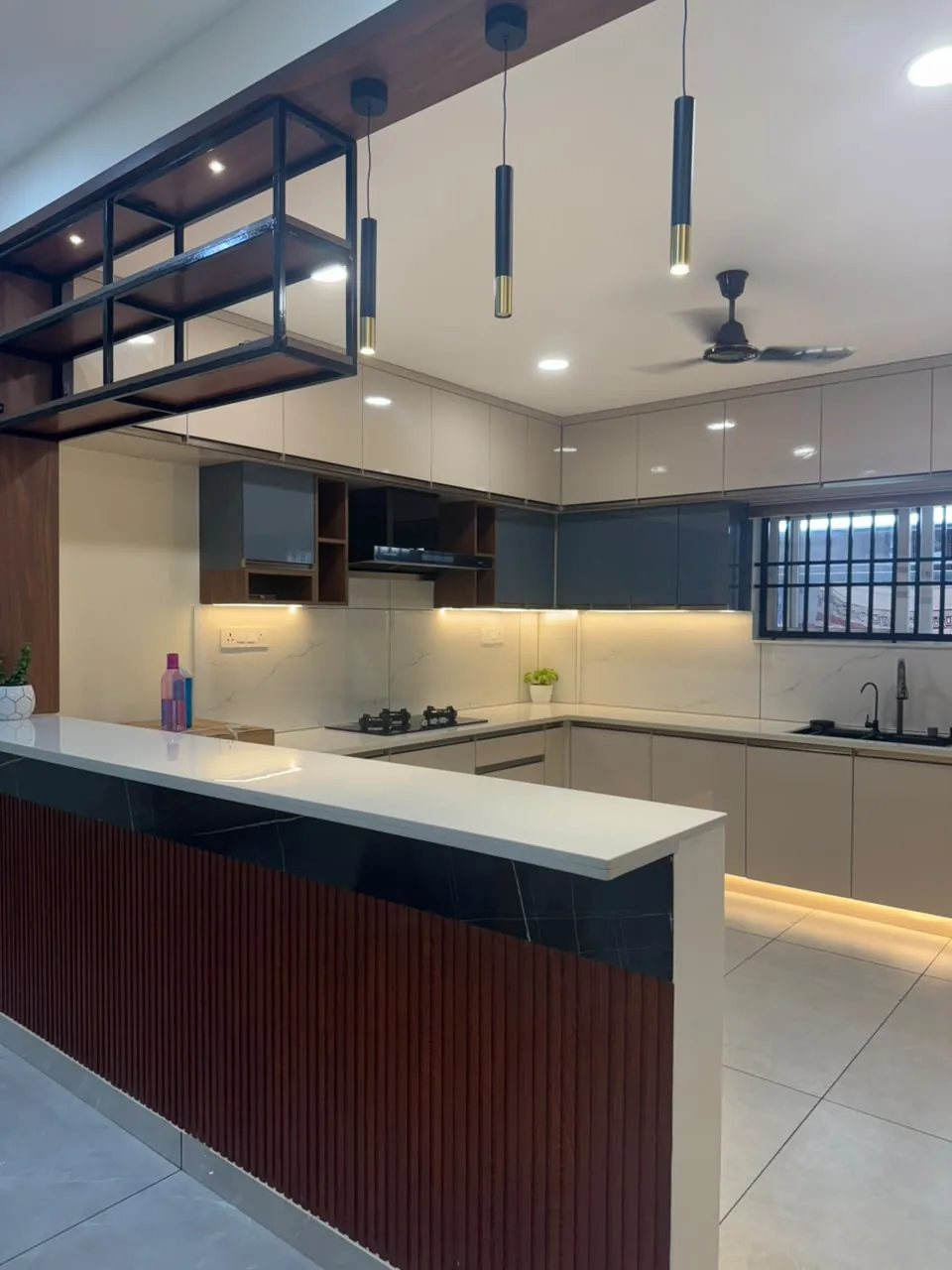 Modular kitchen breakfast counter with fluted wood front, black stone top and pendant lighting