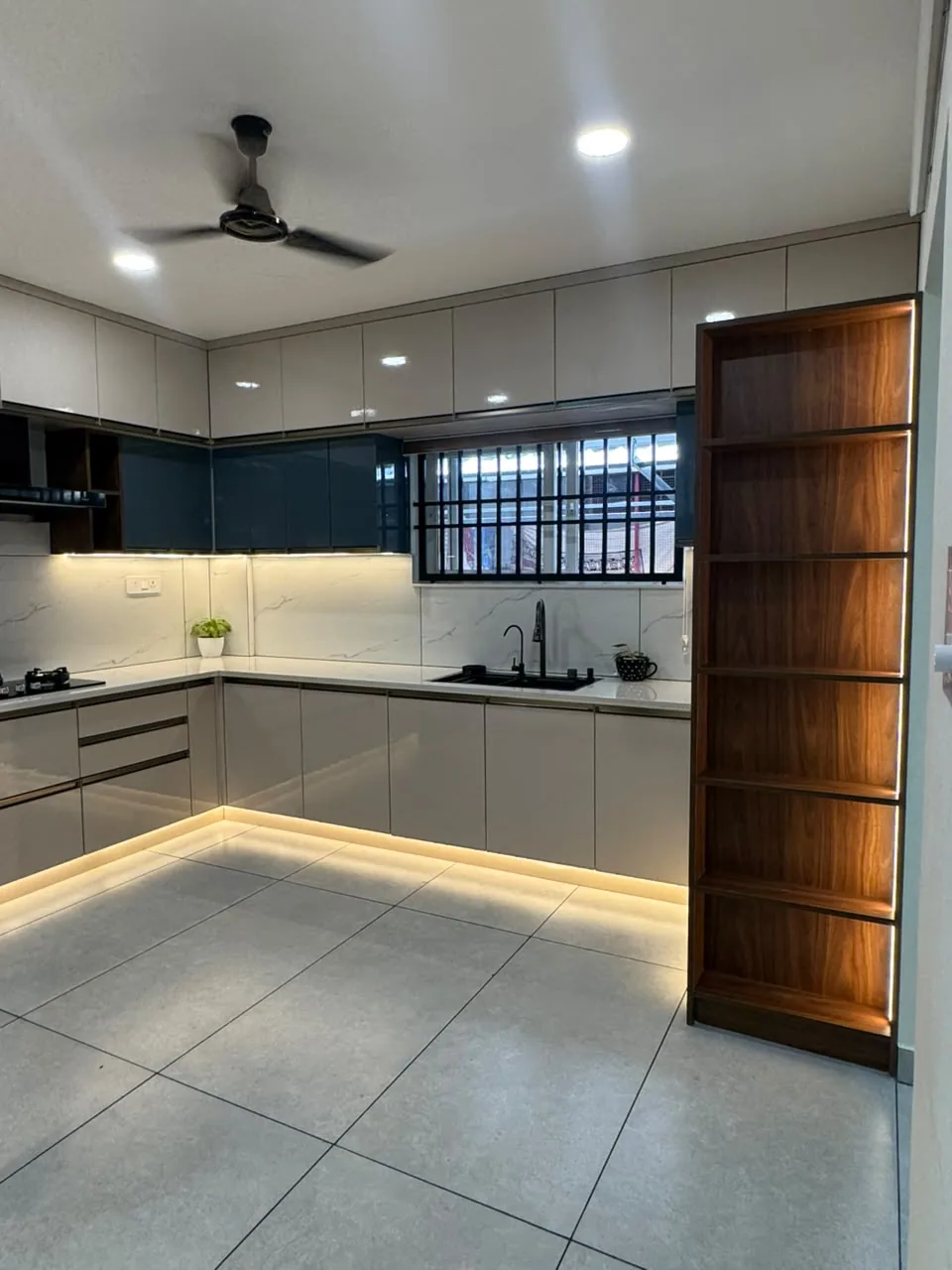 Lit wooden open-shelf display tower closing the end of a modular kitchen run